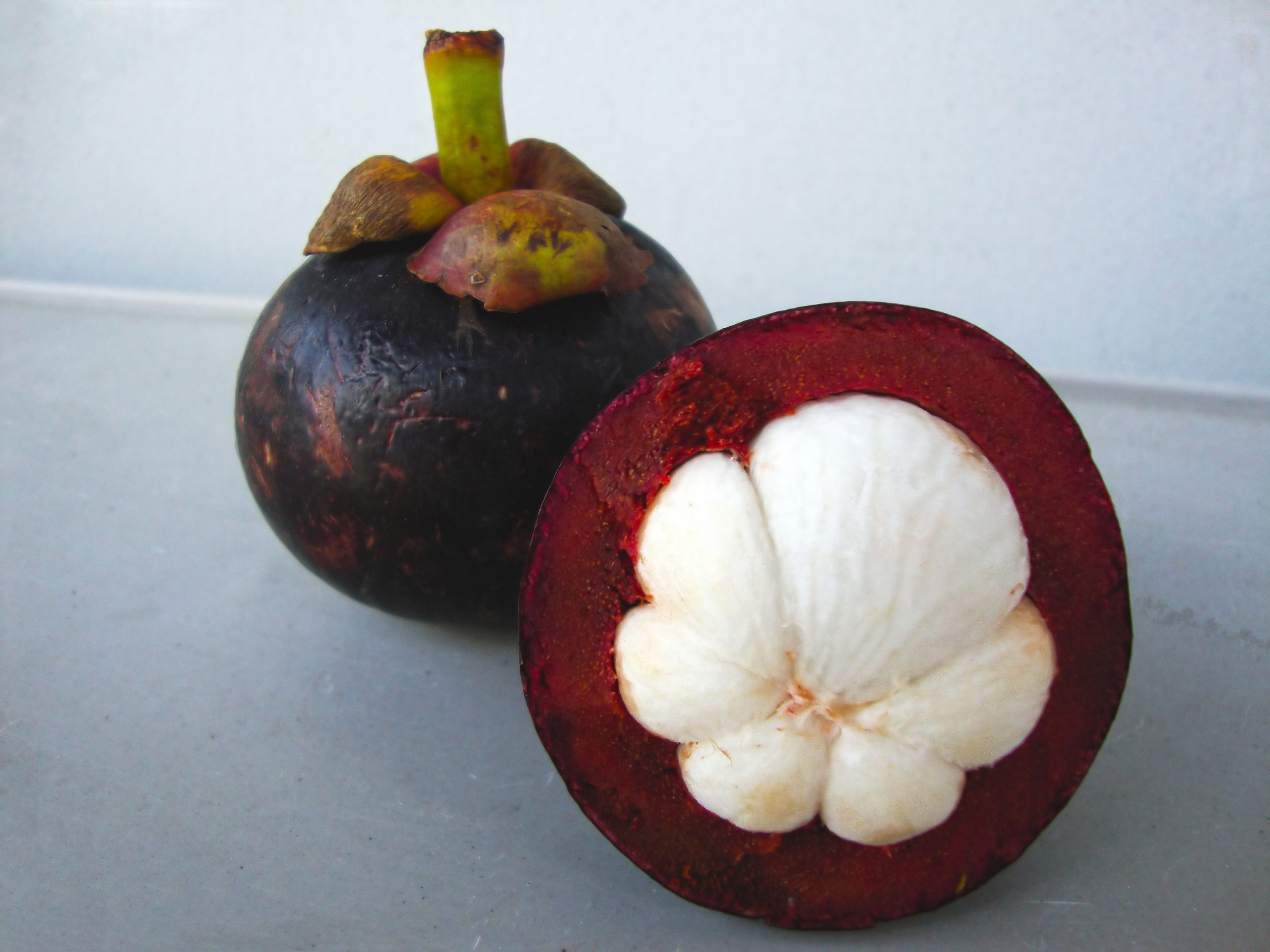 Opened fresh mangosteen with white segments and thick purple rind